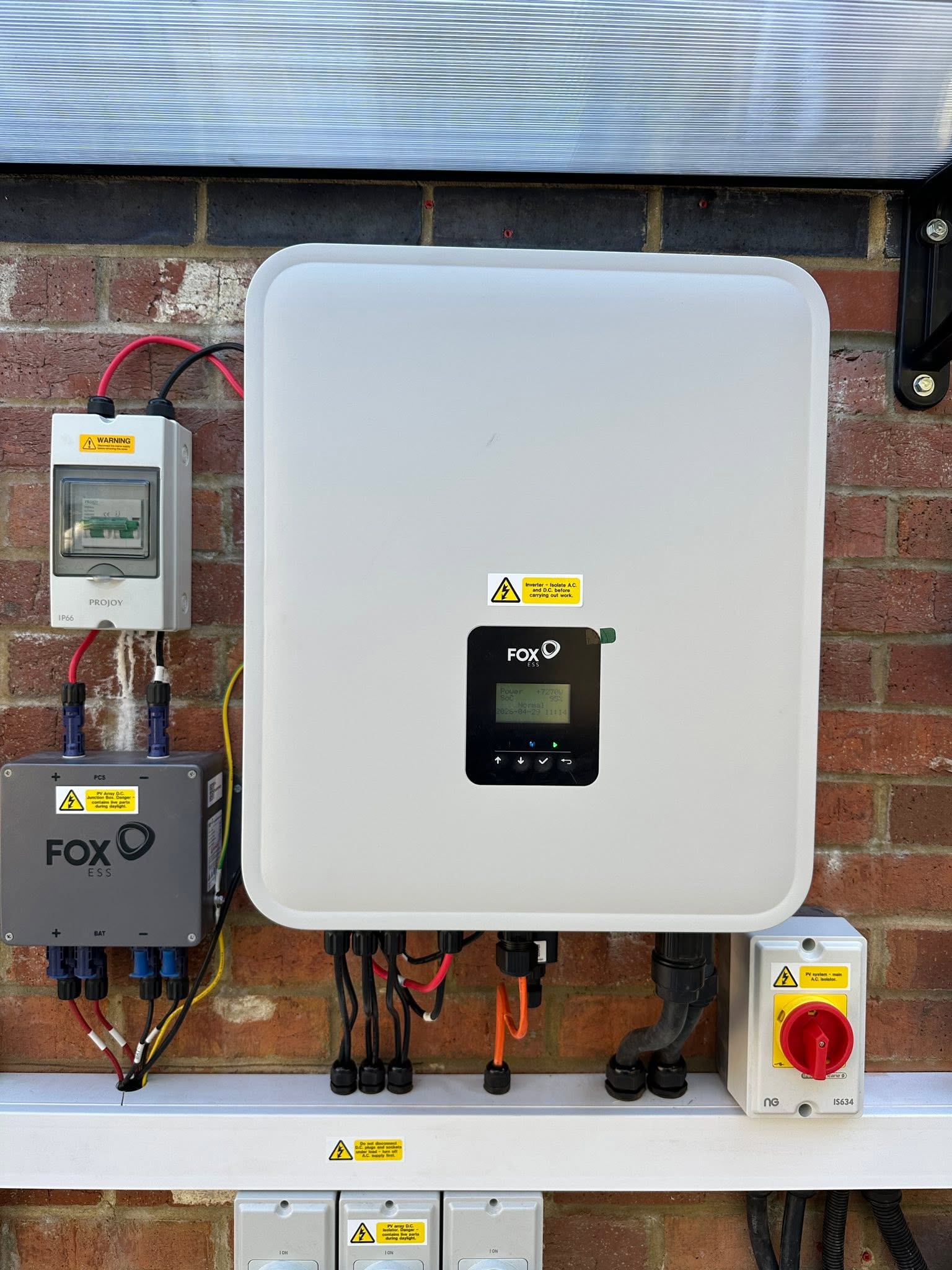 A Fox ESS hybrid inverter with isolators mounted on an inside wall