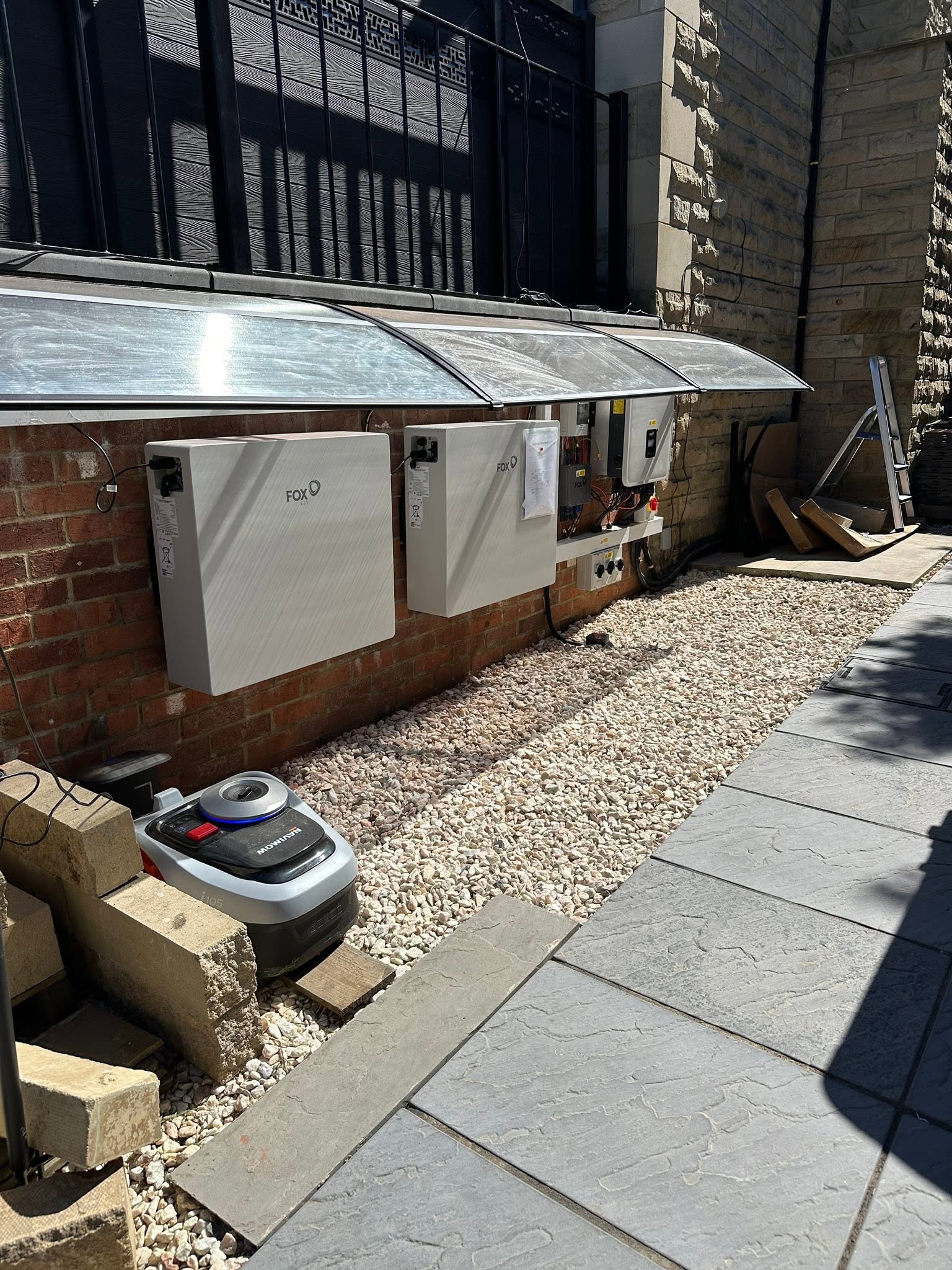 Batteries and inverter mounted outside along a brick wall