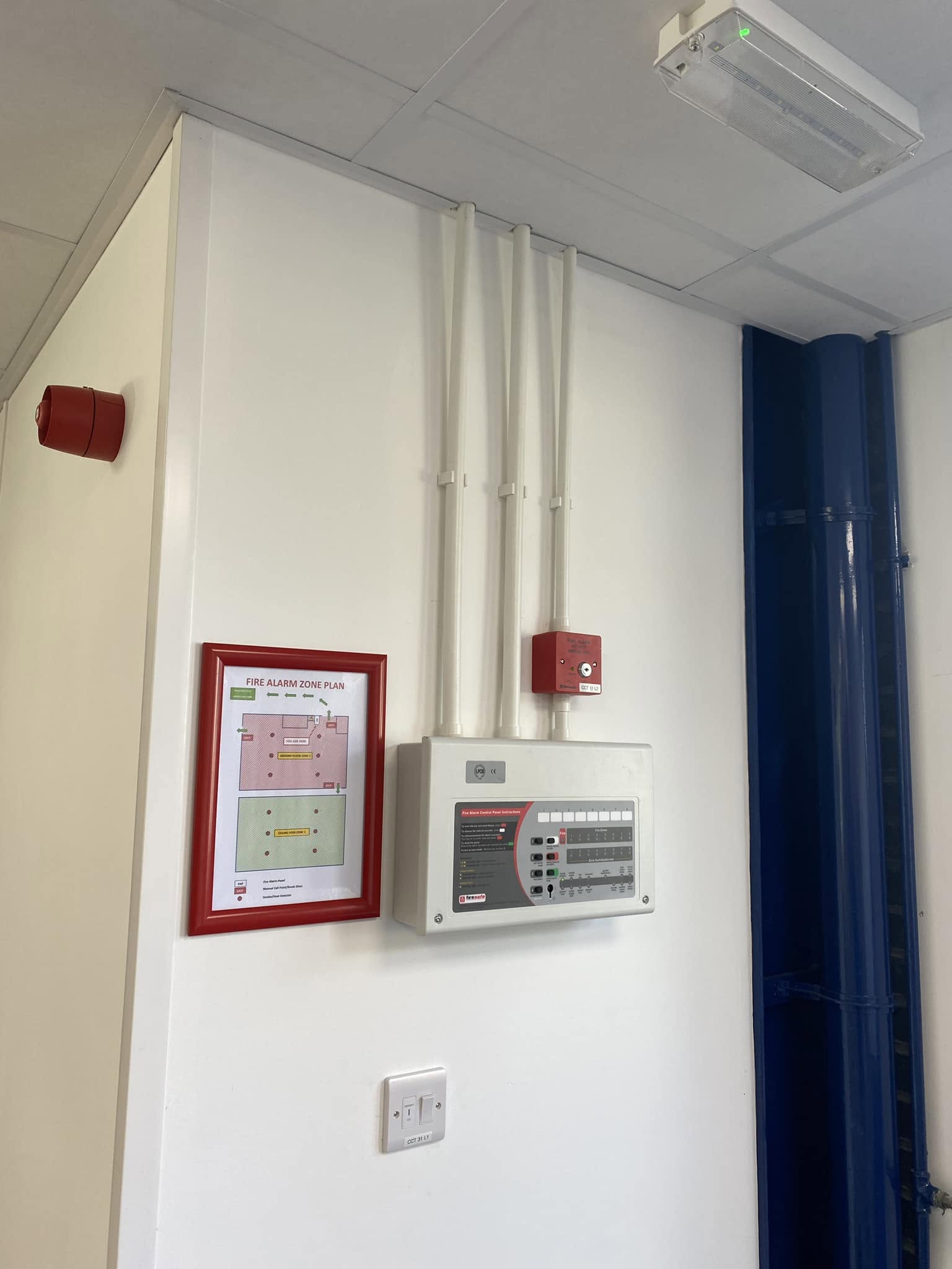 A wall-mounted control panel and conduit in a commercial room